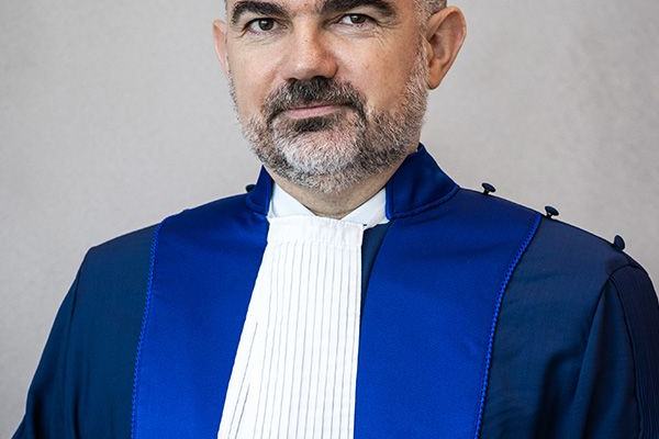 Portrait d’un homme portant une robe de magistrat bleue à rabat blanc.