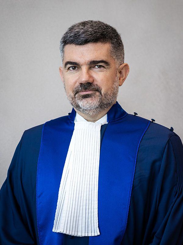 Portrait d’un homme portant une robe de magistrat bleue à rabat blanc.