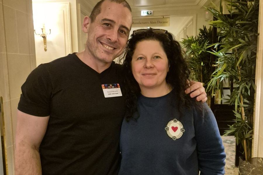 Photo d’un homme et d’une femme qui posent côte à côte, souriants, dans un couloir ; l’homme porte un badge FRnOG au nom de Raphael Maunier.