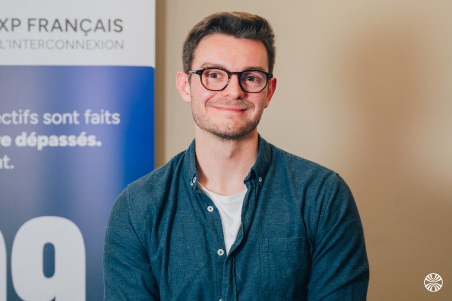 Portrait d’un homme souriant en chemise bleue, devant un kakémono France-IX.