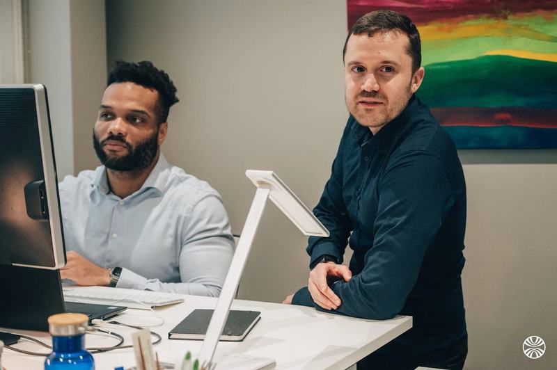 Deux personnes à un bureau, devant un écran d’ordinateur.
